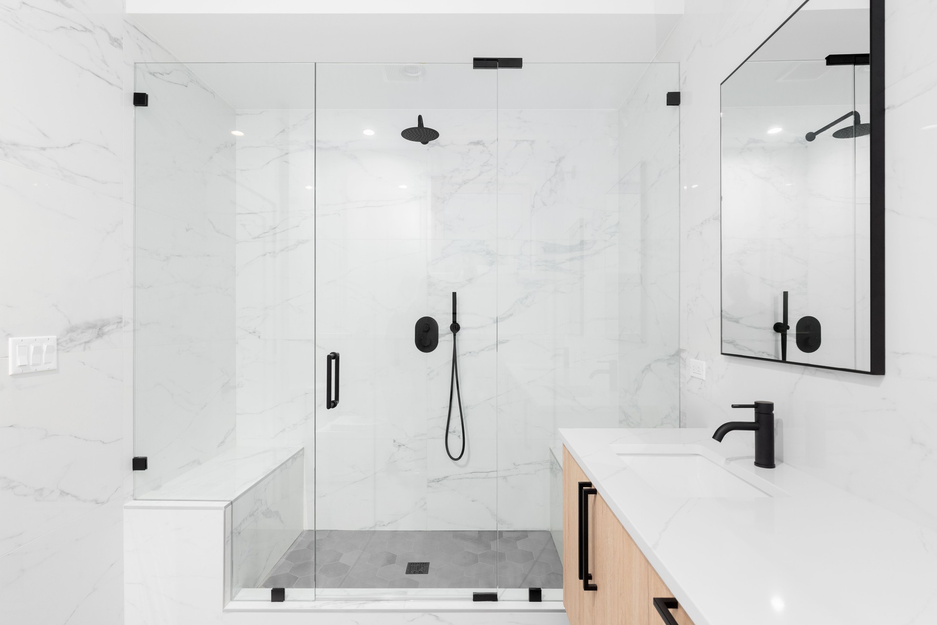 A modern bathroom with a wood cabinet and a large walk-in shower.